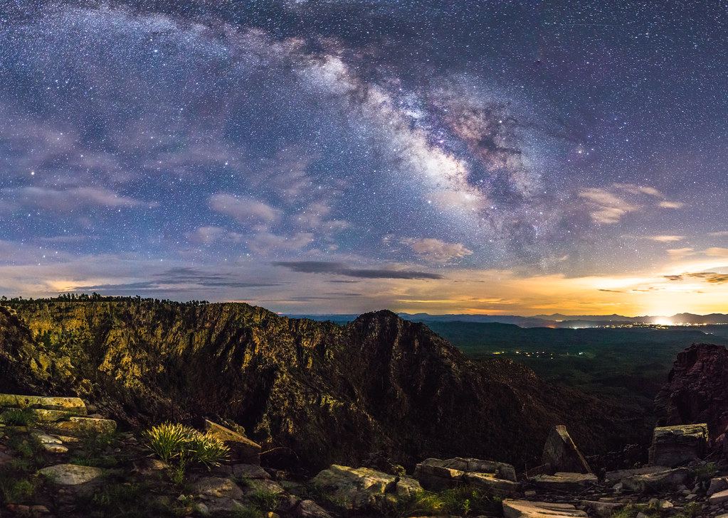 Starry night sky with the Milky Way galaxy visible over a rocky mountain ridge at dusk.